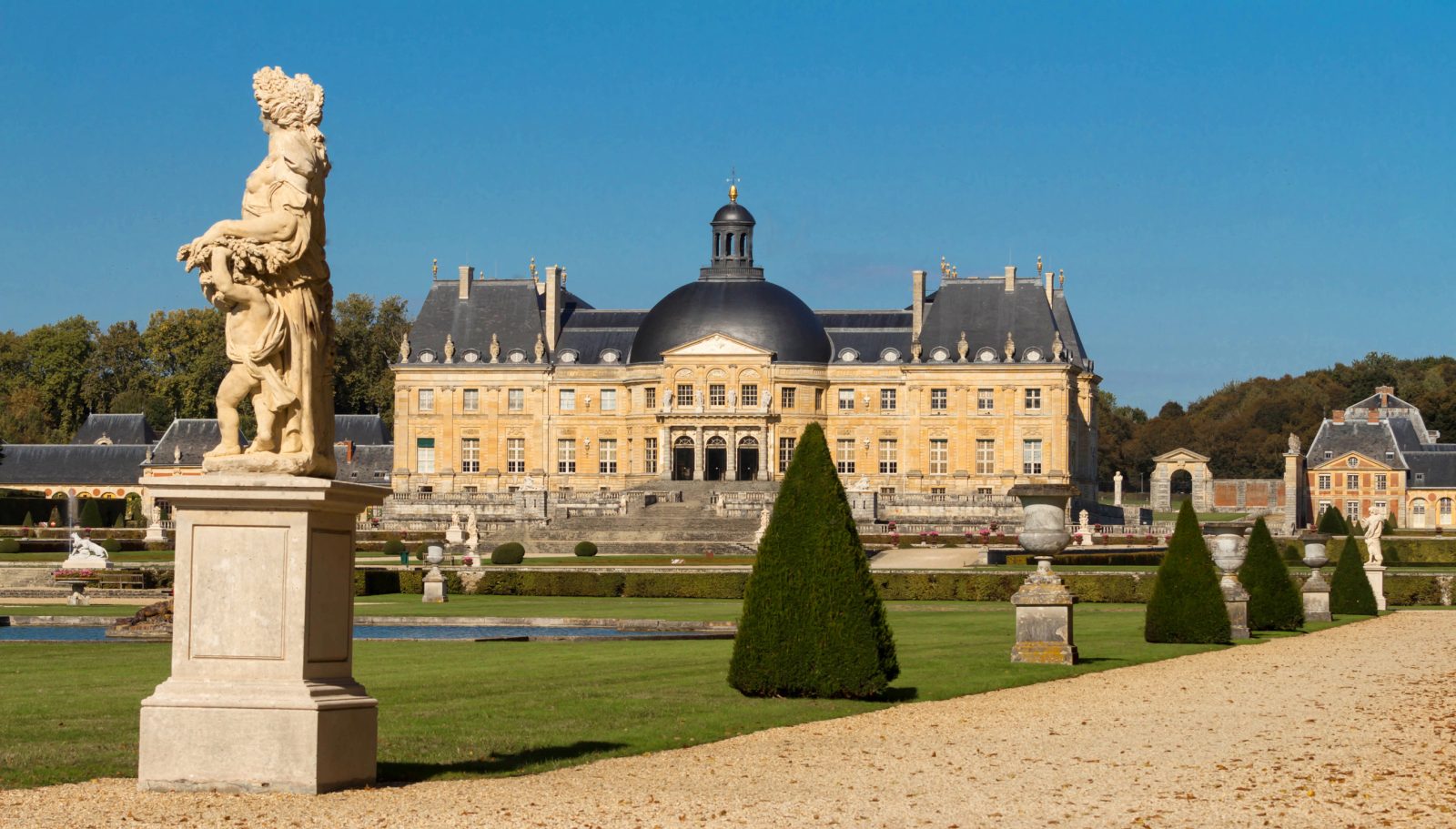 法國沃子爵城堡（Château de Vaux-le-Vicomte）的正面景觀。前景是法式花園，有修剪整齊的樹木、雕像和礫石步道，背景是帶有黑色圓頂的古典主義風格城堡。
