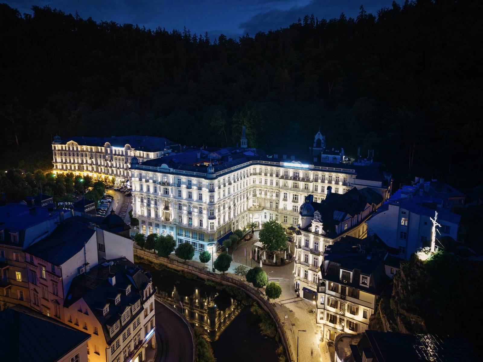 卡羅維瓦利 Grandhotel Pupp 夜間空拍，河畔建築與森林山谷