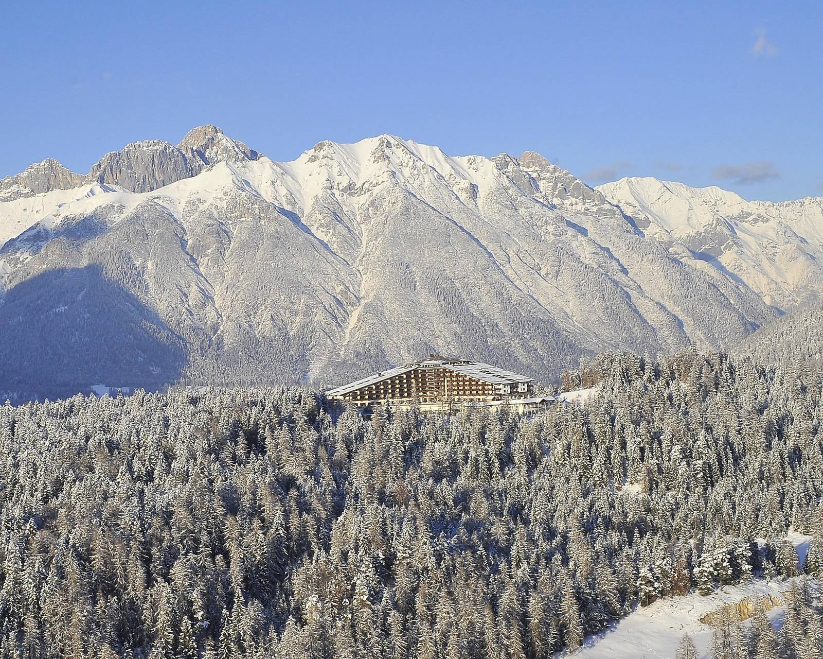 冬季雪林中的 Interalpen-Hotel Tyrol 與背後山脈