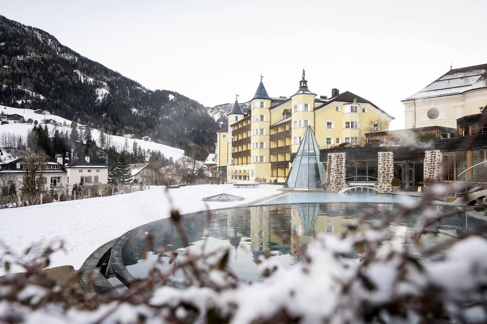 ADLER Spa Resort DOLOMITI 雪季的戶外泳池與飯店外觀
