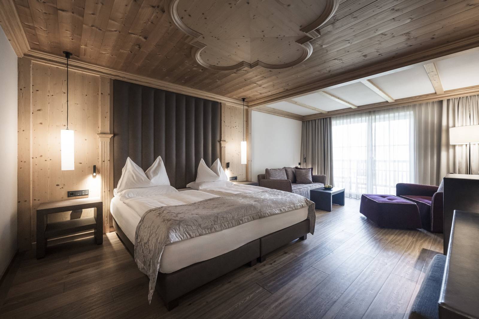 ADLER Spa Resort DOLOMITI 木雕天花板客房的床與起居角落