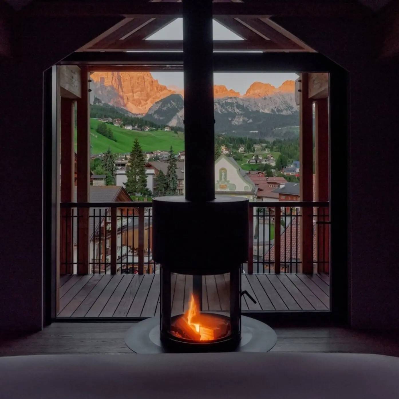 Aman Rosa Alpina Premier Suite 壁爐與窗外的夕照山峰