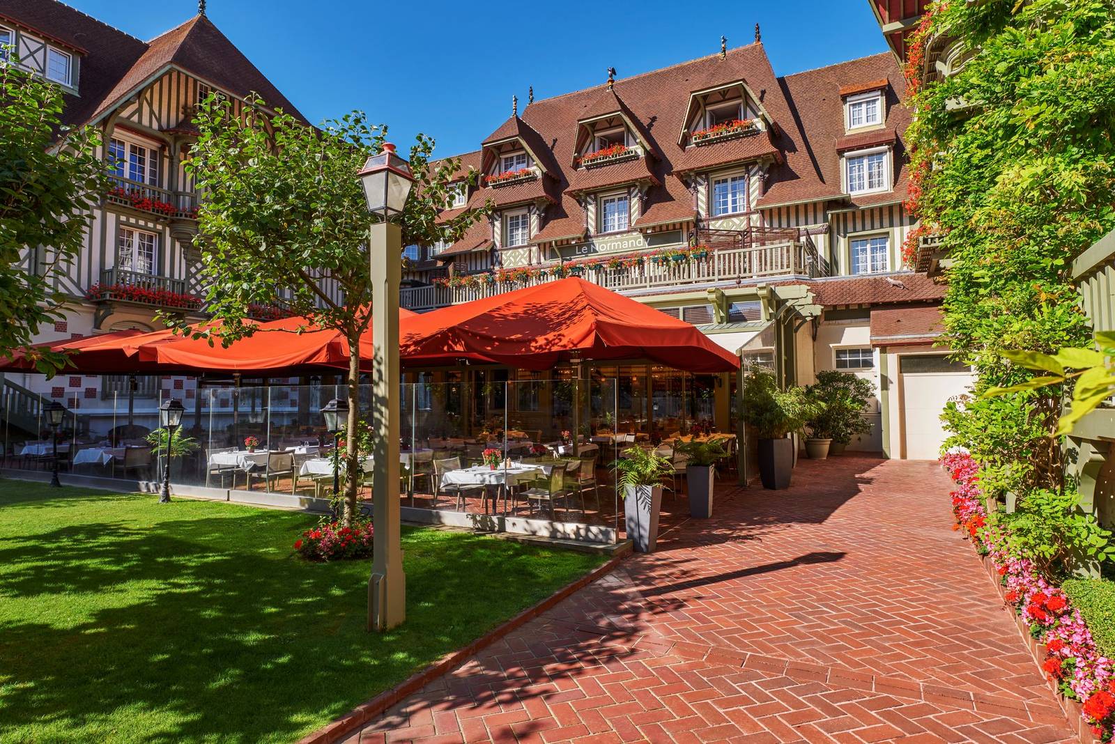 多維爾 Hôtel Barrière Le Normandy 中庭花園的紅色陽傘與磚道