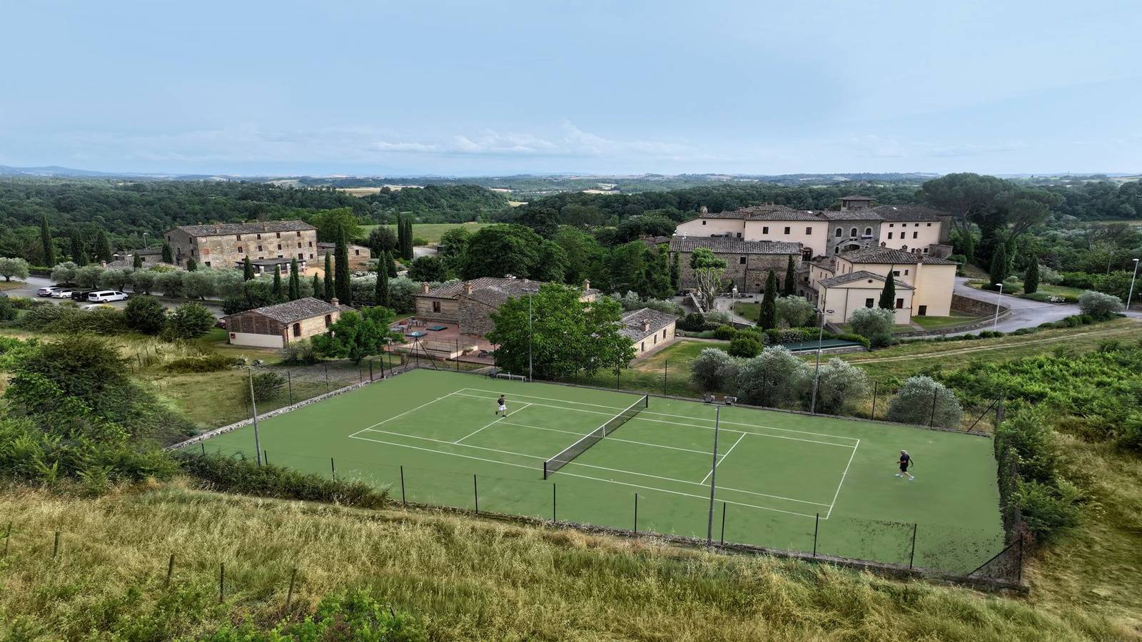 Castel Monastero 山丘上的網球場與遠方村落