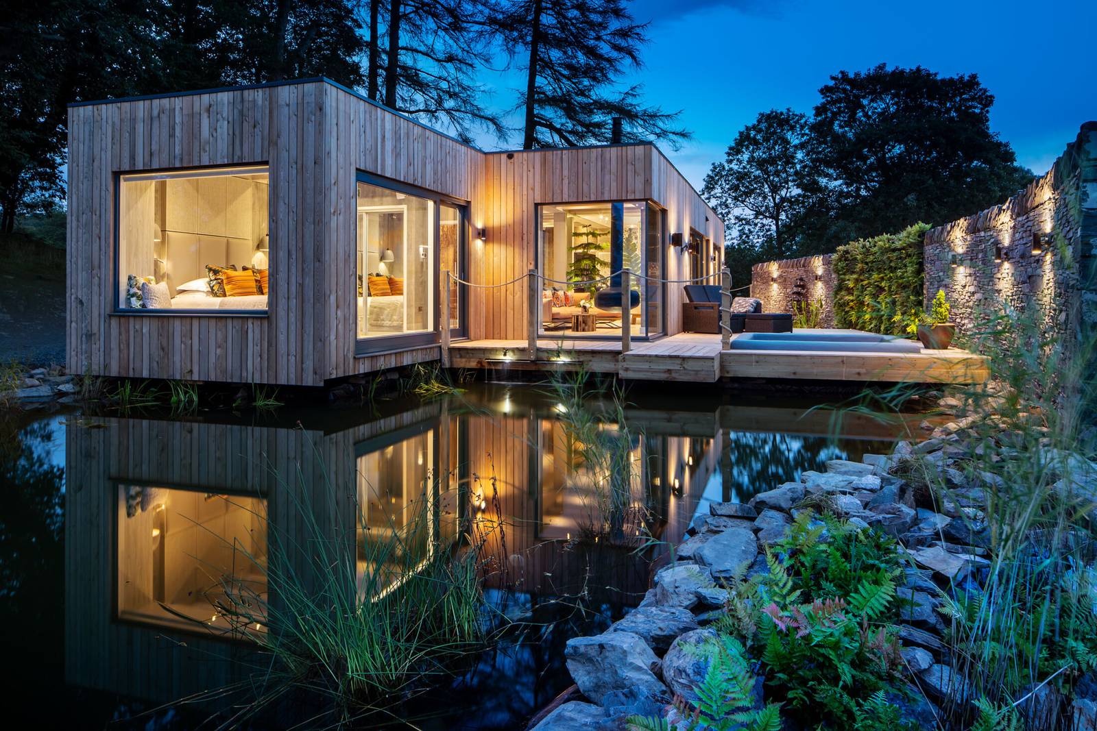 Gilpin Hotel 木造 Spa 套房夜景，建築延伸到池塘上方