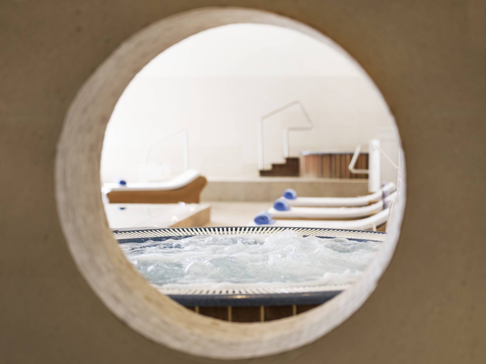 透過圓窗看 Hotel Excelsior Dubrovnik Spa 的按摩池與躺椅