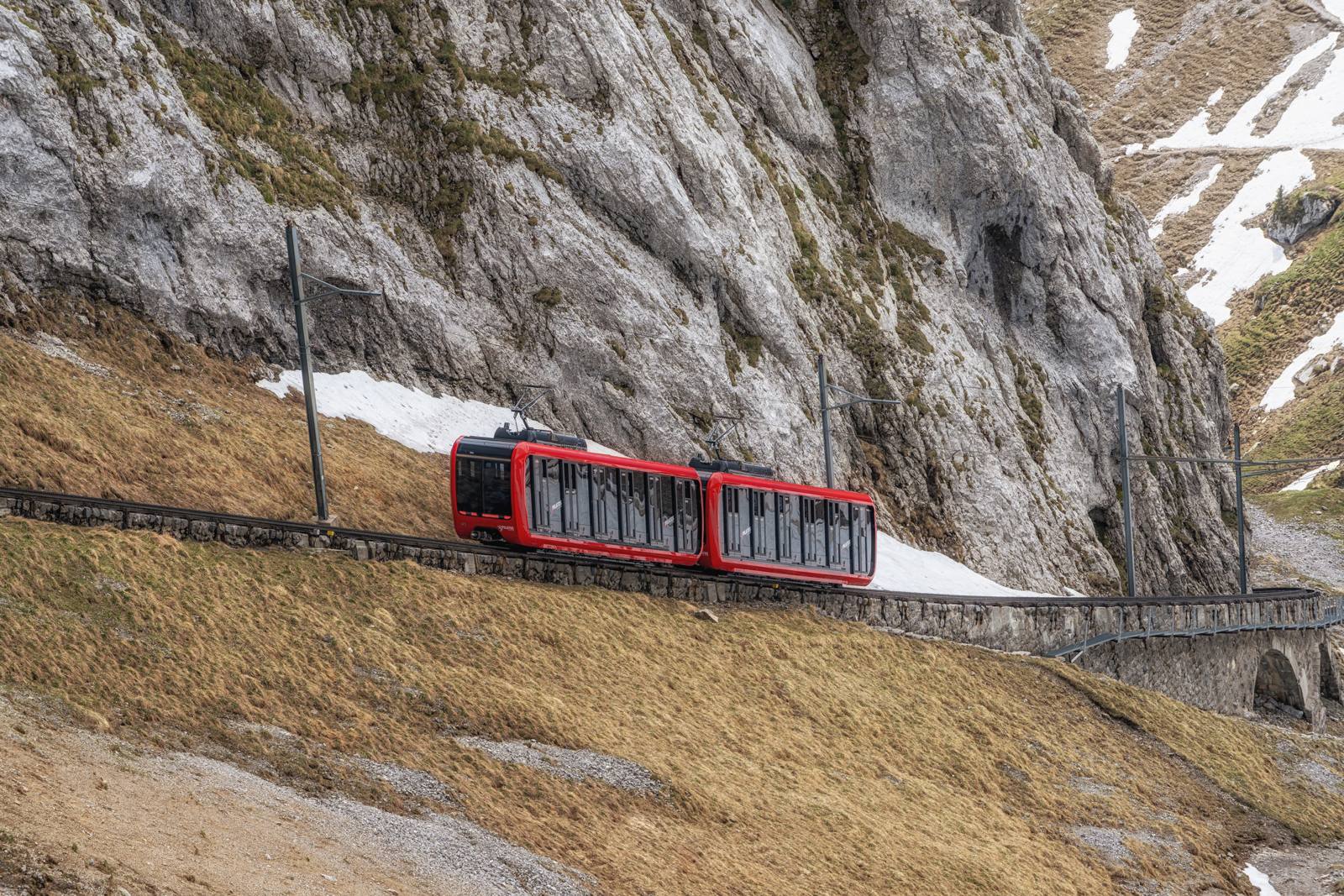 皮拉圖斯紅色齒軌火車行經岩壁與殘雪旁