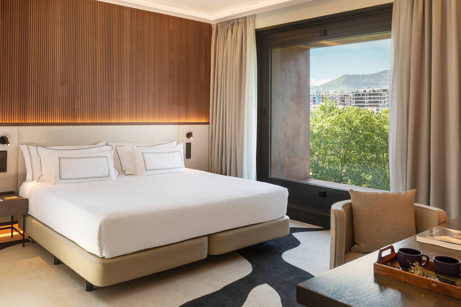 畢爾包 Meliá Bilbao 客房雙人床與窗外綠樹